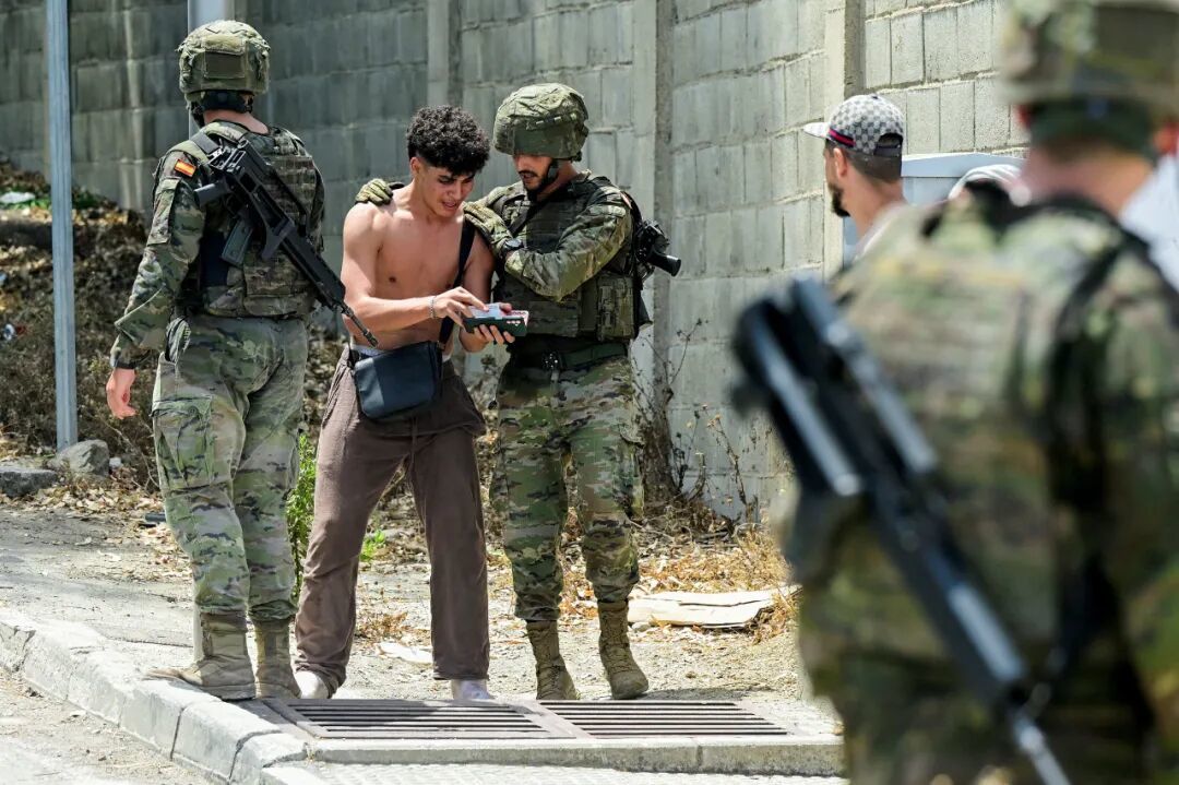 8月1日,在西班牙飞地休达,西班牙士兵盘问一名从摩洛哥入境的非法移民 / 图源:新华社